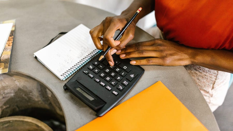 invoicing for freelancers, man using calculator to crunch some numbers