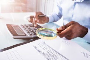 invoice generator, man working with a magnifying glass on his documents