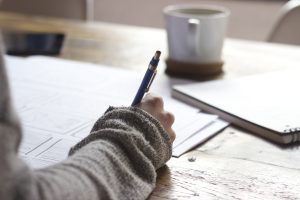 person holding pen writing on a book, financial projections