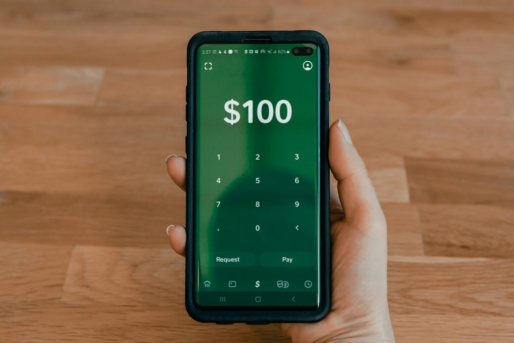 Close-up of smartphone displaying Cash App's borrow interface with loan amount selection, terms display, and approval screen, demonstrating the user-friendly borrowing process for small-dollar loans.